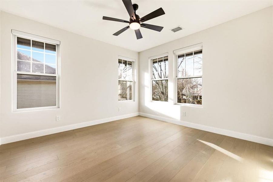 Spare room featuring light wood finished floors, ceiling fan, and healthy amount of natural light