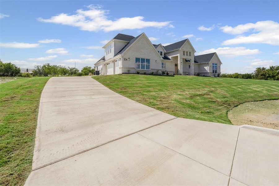 Modern inspired farmhouse featuring an attached garage, driveway, a front yard, and brick siding Modern inspired farmhouse featuring an attached garage, driveway, a front yard, and brick siding