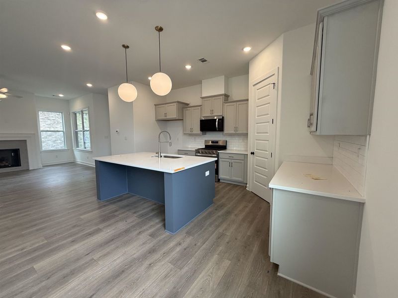Modern kitchen featuring a blue-paneled island with a white countertop and a gooseneck faucet