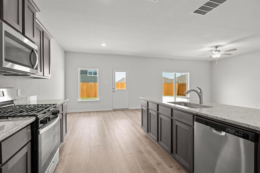 Kitchen featuring stainless steel appliances, light stone countertops, light wood finished floors, a ceiling fan, and recessed lighting Kitchen featuring stainless steel appliances, light stone countertops, light wood finished floors, a ceiling fan, and recessed lighting