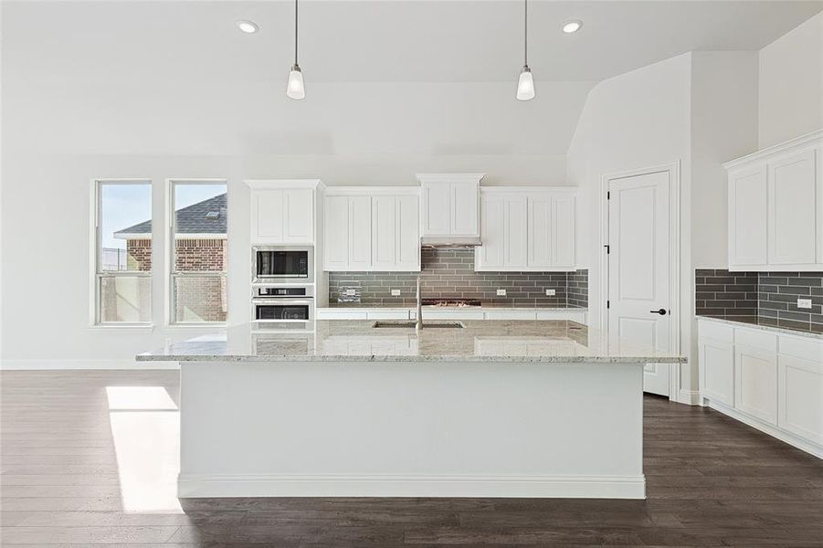 Kitchen with sink, appliances with stainless steel finishes, hanging light fixtures, and dark hardwood / wood-style floors