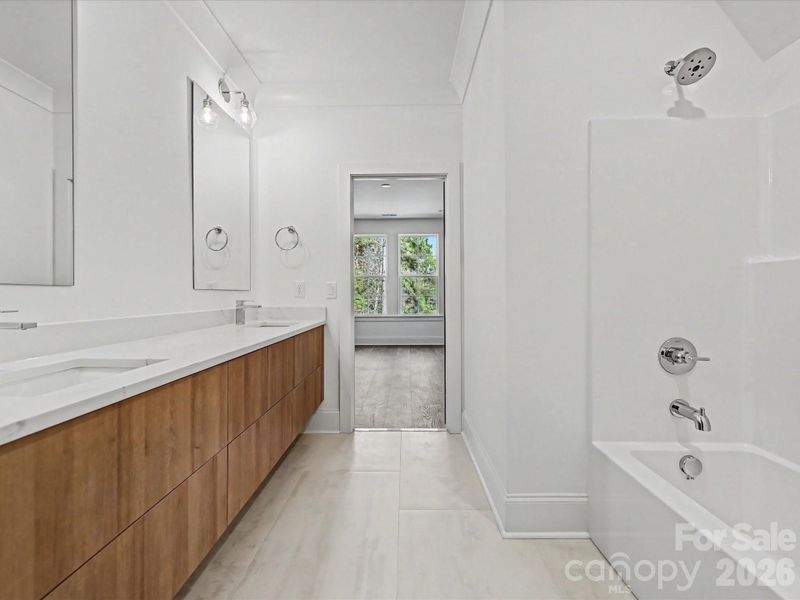 Bright Jack-and-Jill bathroom featuring a dual-sink vanity, modern finishes, and a tub/shower combo with convenient shared access between bedrooms.