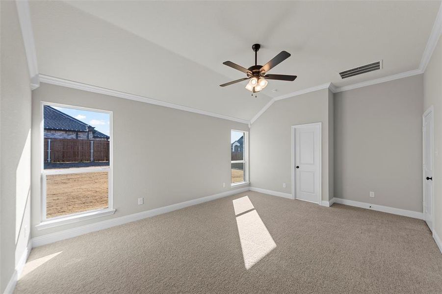 Unfurnished bedroom with ornamental molding, lofted ceiling, light colored carpet, and a ceiling fan