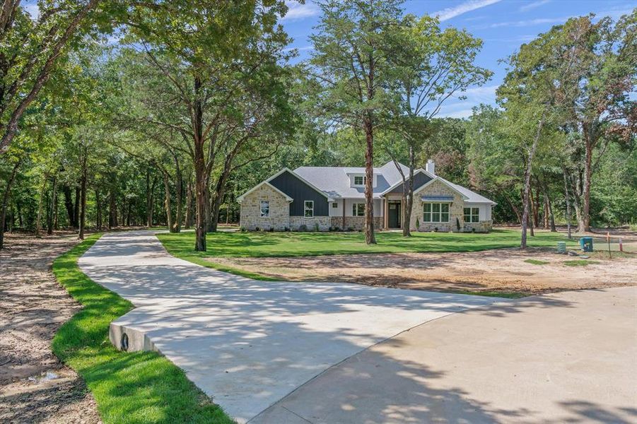 View of front of home featuring stone siding, a chimney, and a front yard with mature trees View of front of home featuring stone siding, a chimney, and a front yard with mature trees