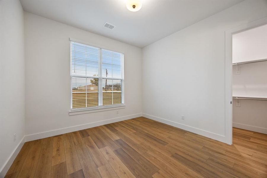 Unfurnished bedroom featuring a walk in closet and light wood-type flooring