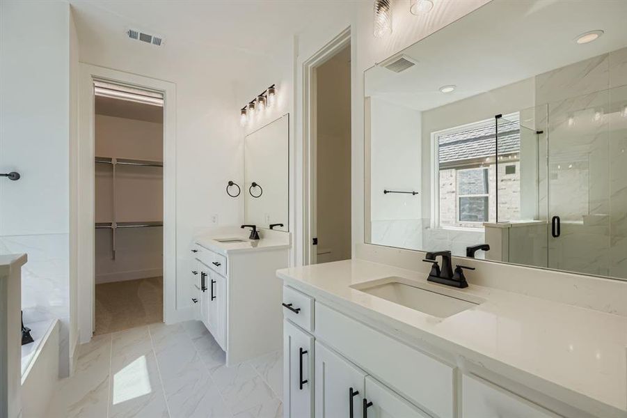 Full bathroom featuring two vanities, a marble finish shower, light marble finish flooring, and a walk in closet Full bathroom featuring two vanities, a marble finish shower, light marble finish flooring, and a walk in closet
