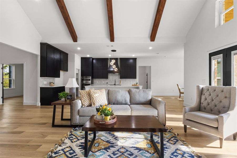 Living room with recessed lighting, high vaulted ceiling, beamed ceiling, and light wood-type flooring