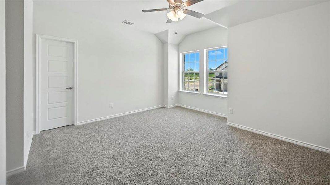 Carpeted empty room featuring ceiling fan and lofted ceiling