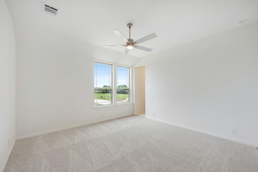 Empty bedroom with carpet flooring, ceiling fan, and double windows overlooking a green yard Empty bedroom with carpet flooring, ceiling fan, and double windows overlooking a green yard