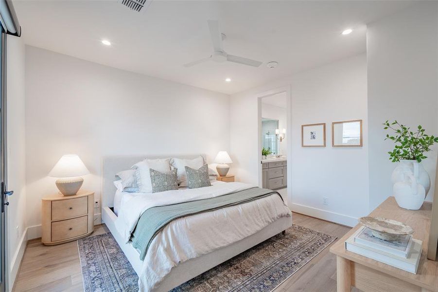 Bedroom with ensuite bath, ceiling fan, and light hardwood / wood-style floors