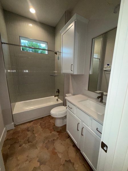 Custom tile flooring and a well-lit vanity create a refreshing bathroom space.