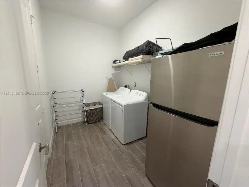 Utility space featuring wood-finish tile flooring, white appliances, and built-in wire shelving