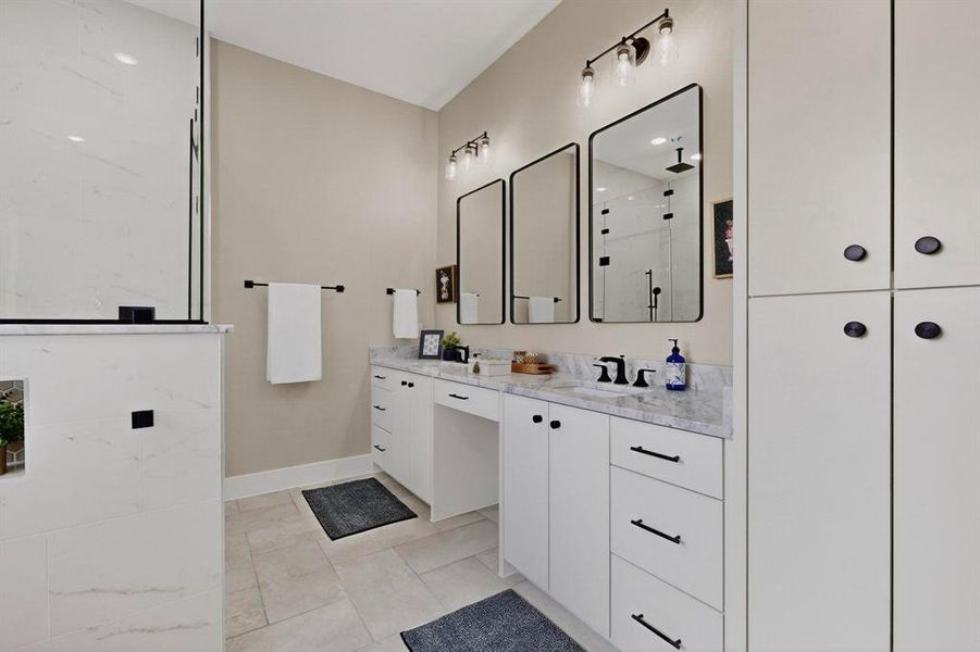 Full bathroom featuring vanity, a marble finish shower, and light tile patterned flooring