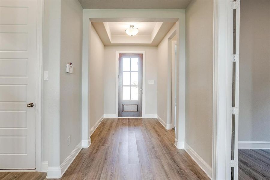 Doorway with wood-type flooring and a tray ceiling