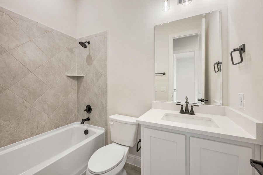 Bathroom with tub-shower combo, diagonal tile surround, white vanity, and dark bronze fixtures