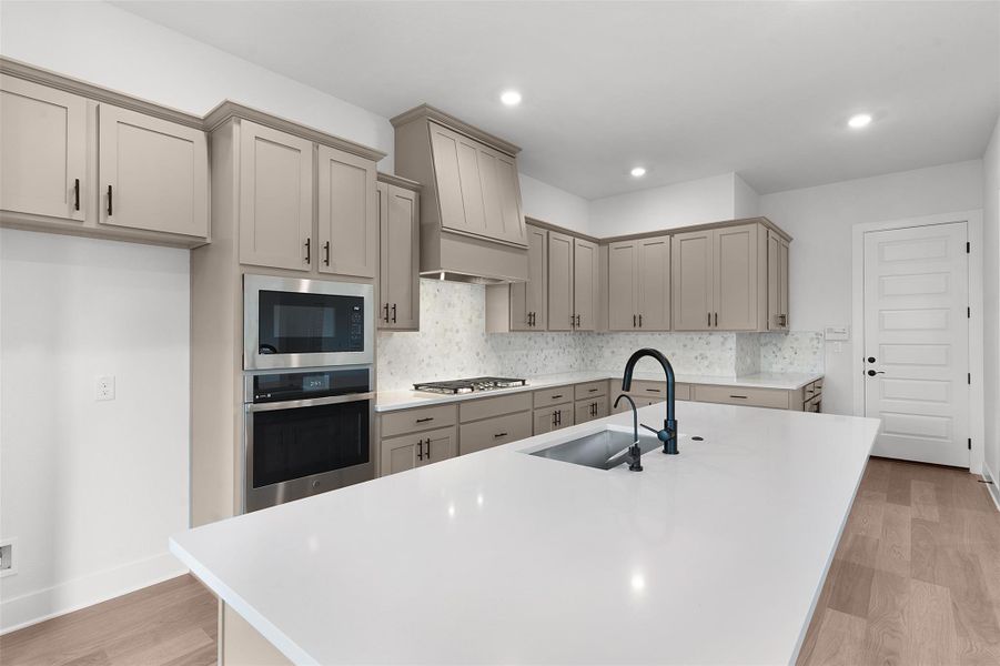 Kitchen featuring stainless steel appliances, tasteful backsplash, gray cabinets, a center island with sink, and recessed lighting