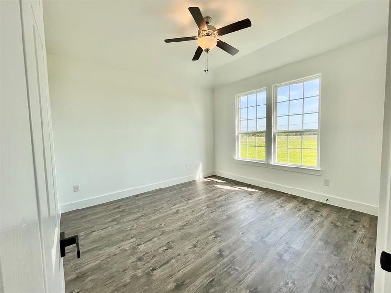 Empty room with ceiling fan, baseboards, and dark wood-style floors Empty room with ceiling fan, baseboards, and dark wood-style floors