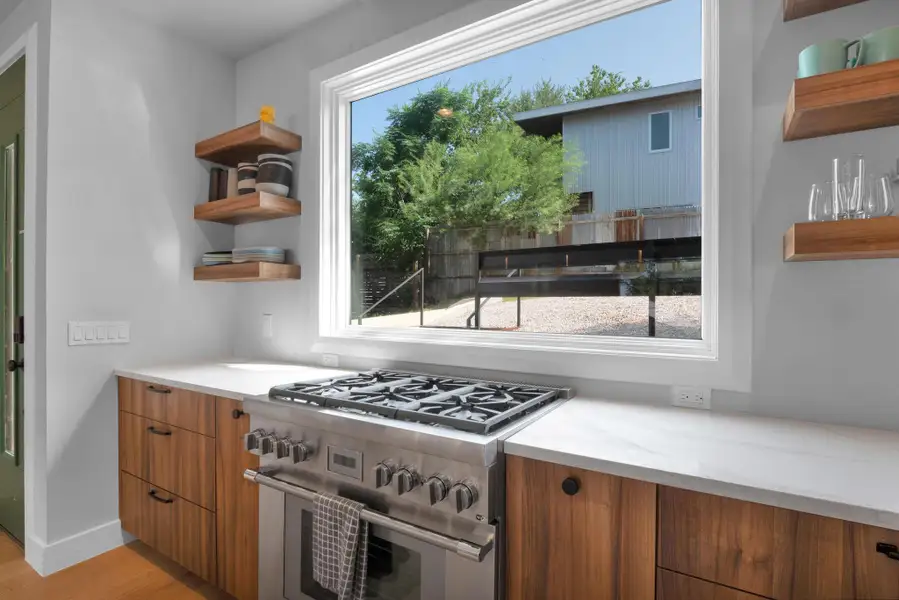 Kitchen with high end stove, open shelves, light wood finished floors, brown cabinets, and modern cabinets