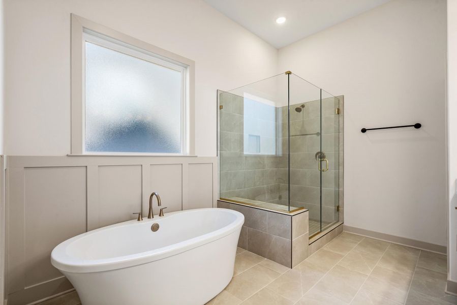 Bathroom featuring a stall shower, a freestanding tub, and light tile patterned floors