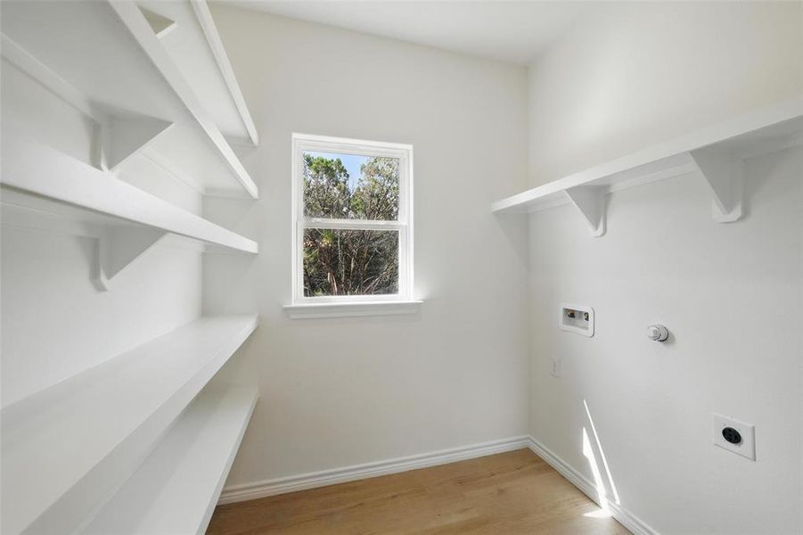 Laundry room featuring hookup for an electric dryer, washer hookup, light wood-type flooring, and baseboards Laundry room featuring hookup for an electric dryer, washer hookup, light wood-type flooring, and baseboards