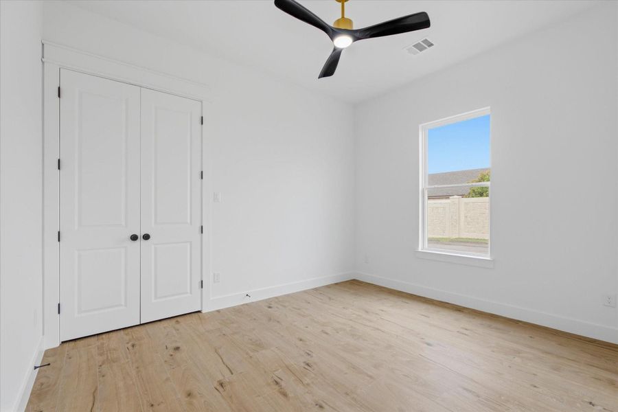Bright & Cozy. Another spacious bedroom offering ultimate flexibility! Complete with warm wood-look flooring, a stylish black-and-gold ceiling fan, and elegant double-door closet storage, it makes the perfect guest suite, nursery, or creative workspac