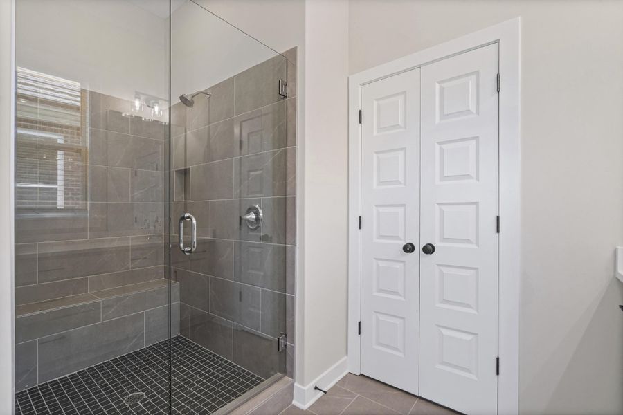 Frameless glass shower enclosure featuring large-format gray wall tile, a built-in shower bench, and a rectangular shower niche Frameless glass shower enclosure featuring large-format gray wall tile, a built-in shower bench, and a rectangular shower niche