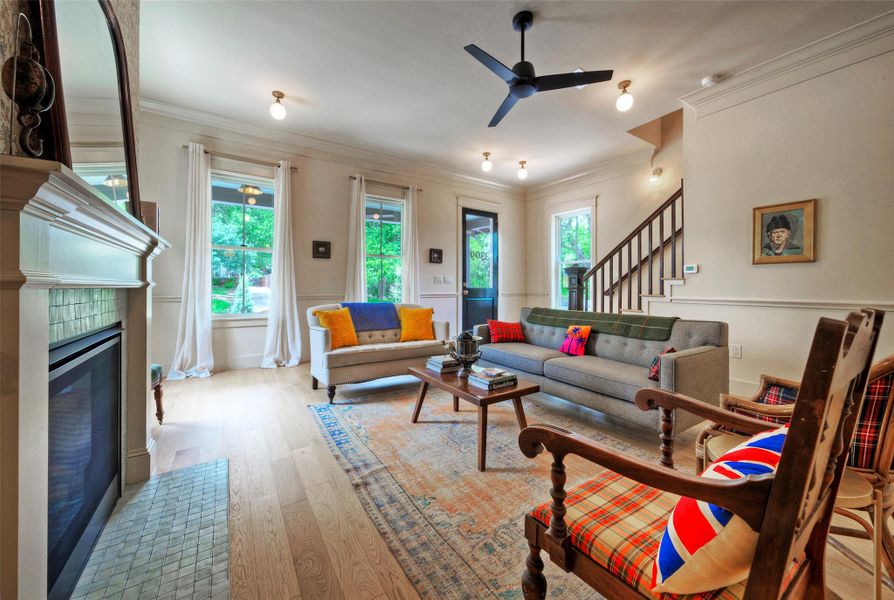 A welcoming living room featuring a cozy fireplace, light hardwood floors, and abundant natural light from multiple windows.