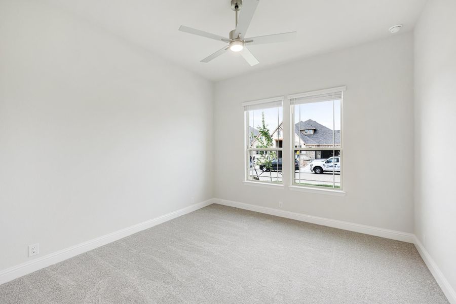 Empty bedroom with light gray carpet, ceiling fan, and two windows with neighborhood view Empty bedroom with light gray carpet, ceiling fan, and two windows with neighborhood view