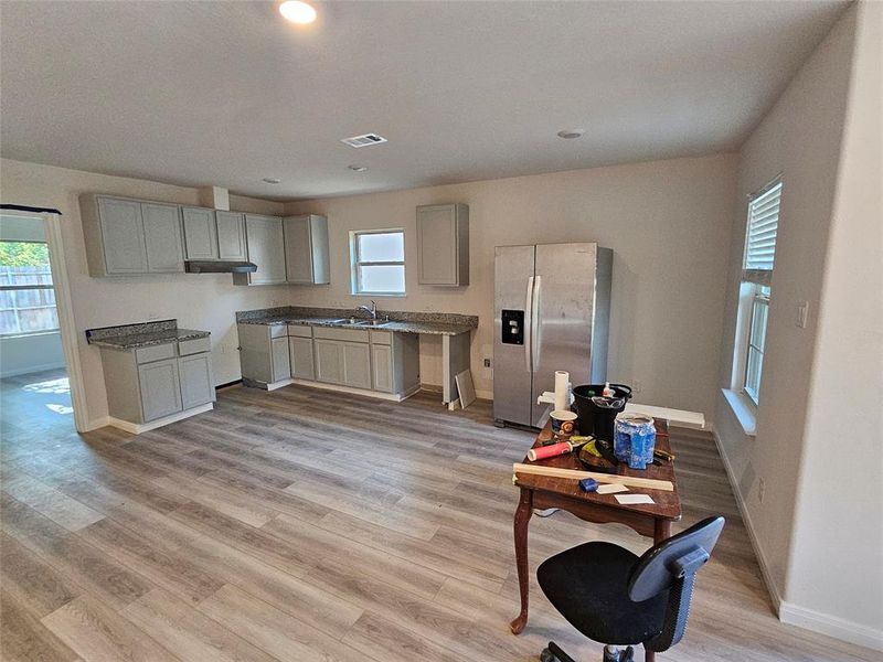 Kitchen featuring light hardwood / wood-style flooring, gray cabinetry, and stainless steel fridge