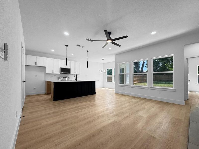 Unfurnished living room with light wood-type flooring, ceiling fan, recessed lighting, and a textured ceiling