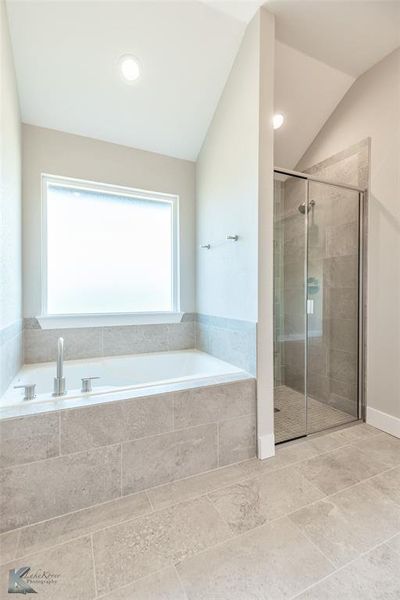 Full bath with a bath, a shower stall, and vaulted ceiling