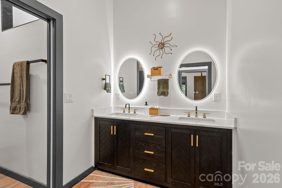 Double sinks greet you in this very design forward bathroom - brass fixtures and a walk in shower await you.