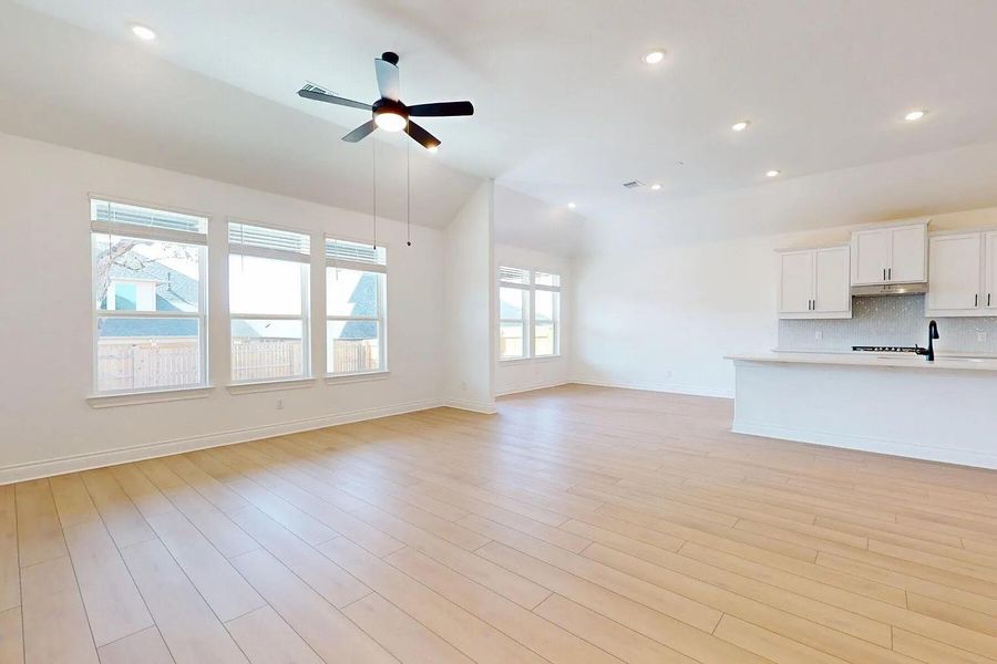 Expansive living area featuring light-toned flooring, recessed lighting, and a ceiling fan