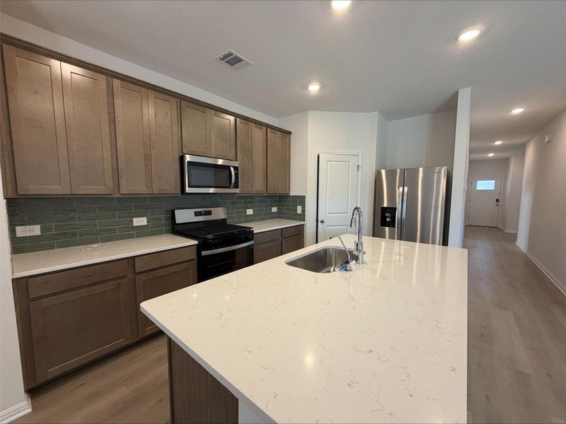 Kitchen featuring stainless steel appliances, light wood-type flooring, light stone counters, decorative backsplash, and recessed lighting