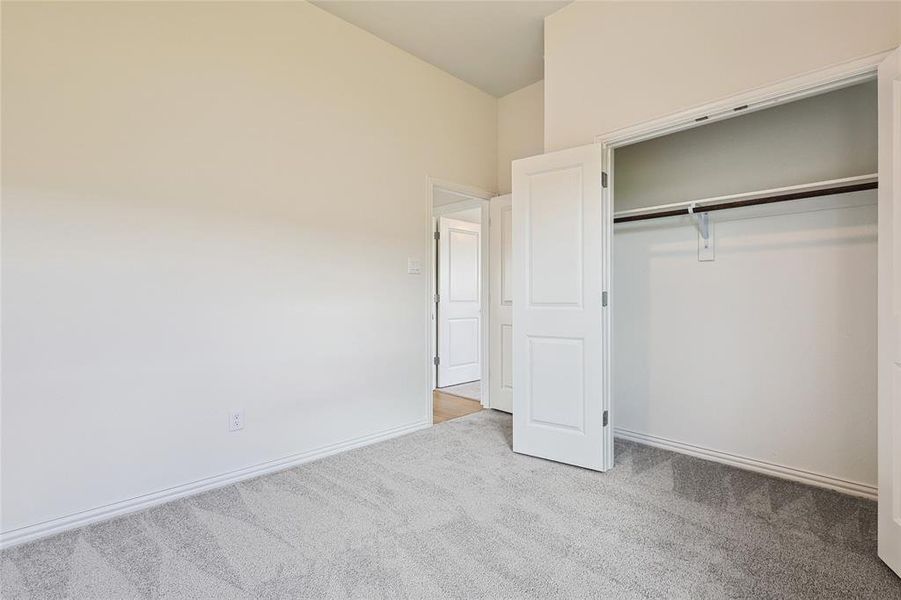 Unfurnished bedroom with a high ceiling, light colored carpet, and a closet