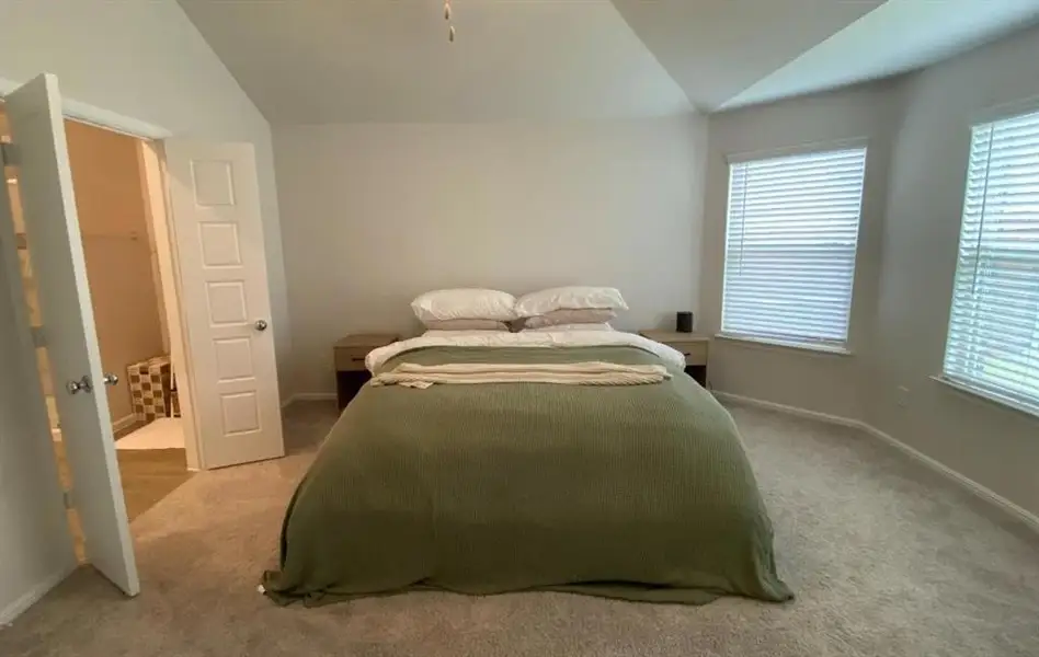 Bedroom featuring vaulted ceiling and carpet floors Bedroom featuring vaulted ceiling and carpet floors