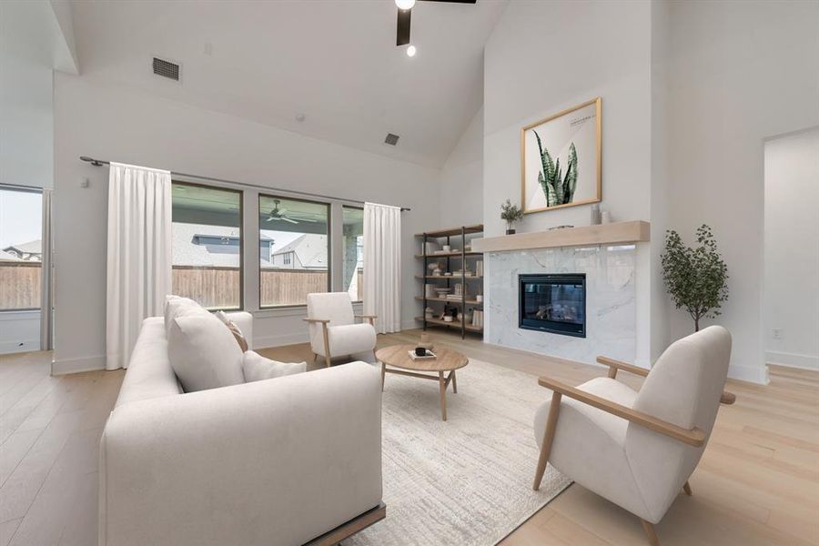 Living room with high vaulted ceiling, light wood-type flooring, a ceiling fan, and a high end fireplace