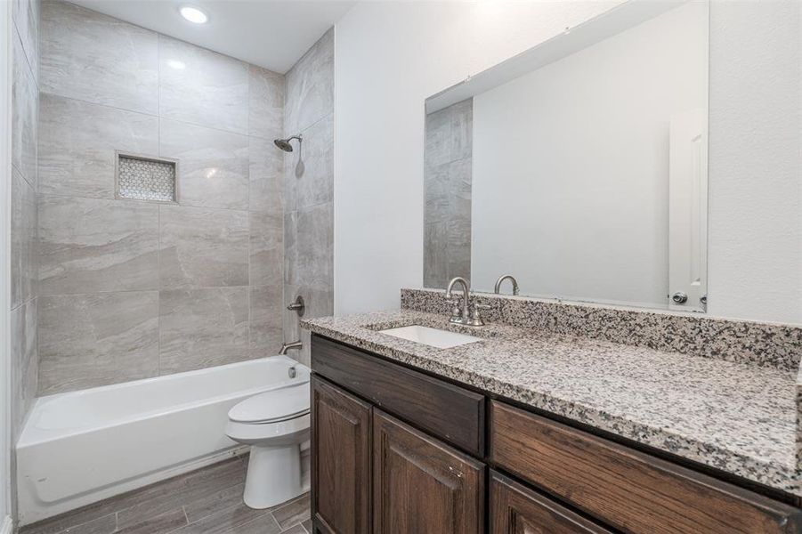 Full bath with shower / bathtub combination, wood finished floors, vanity, and toilet