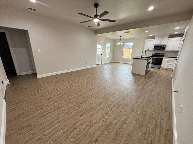 Unfurnished living room featuring recessed lighting, a chandelier, light wood finished floors, and a ceiling fan