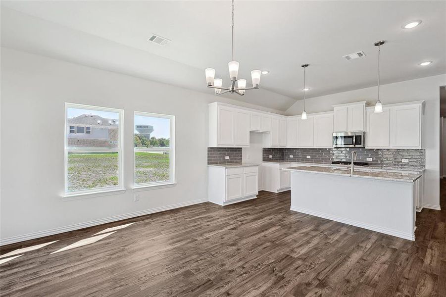 Kitchen featuring a center island with sink, dark hardwood / wood-style floors, and white cabinetry