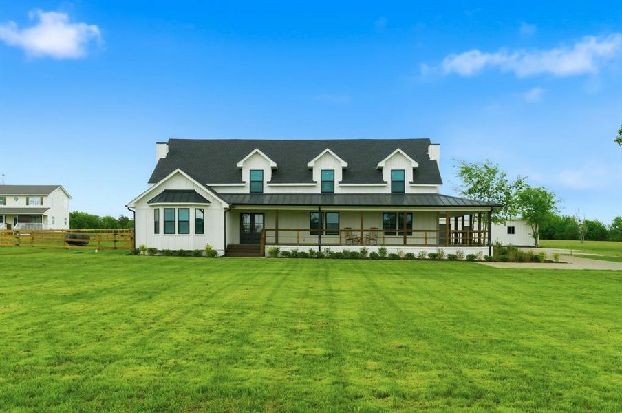 The property features a white exterior, a dark roof, and a covered porch The property features a white exterior, a dark roof, and a covered porch