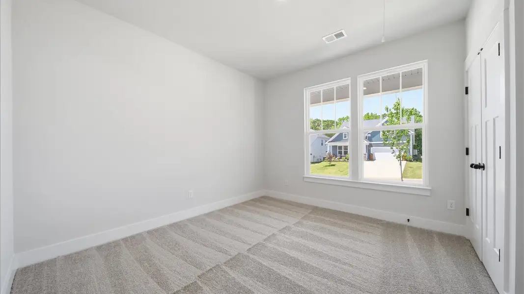 Tasteful bedroom with plush carpet, a walk-in closet, and large windows for abundant natural light at Iris Meadows