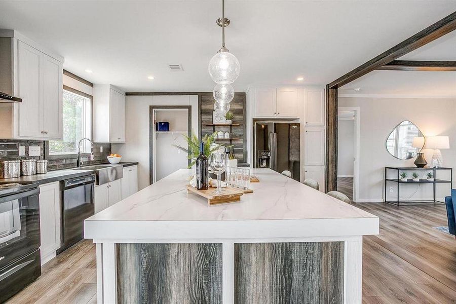 Kitchen featuring white cabinetry, light stone counters, pendant lighting, a kitchen island, and black appliances