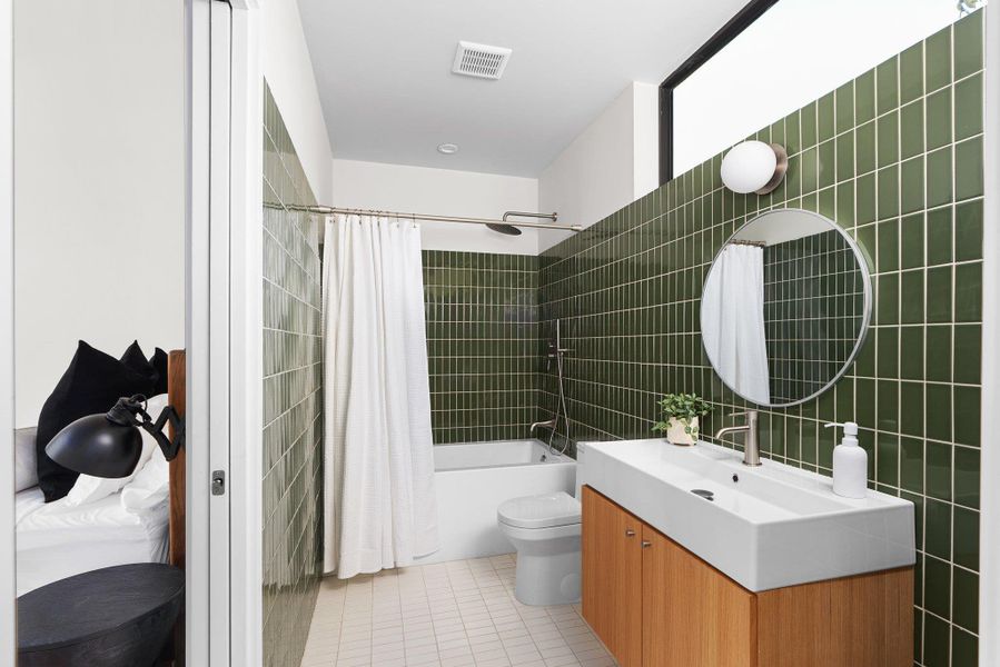 Full bath with tile walls, shower / tub combo with curtain, vanity, and light tile patterned floors Full bath with tile walls, shower / tub combo with curtain, vanity, and light tile patterned floors