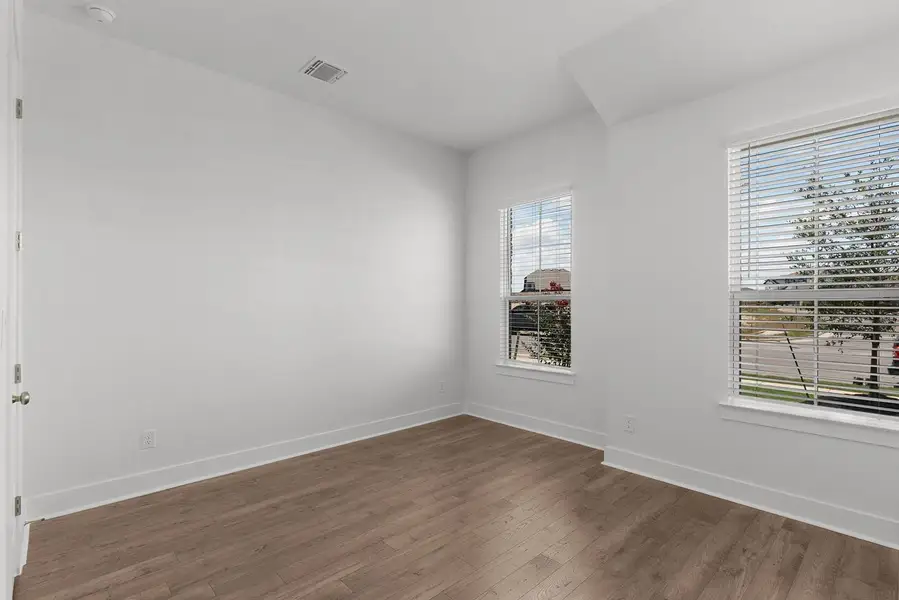 Bright interior space features hardwood-style flooring and natural light through multiple windows.