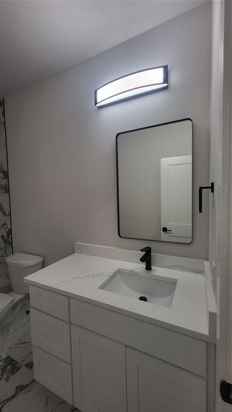 Bathroom with marble finish floor, toilet, and vanity