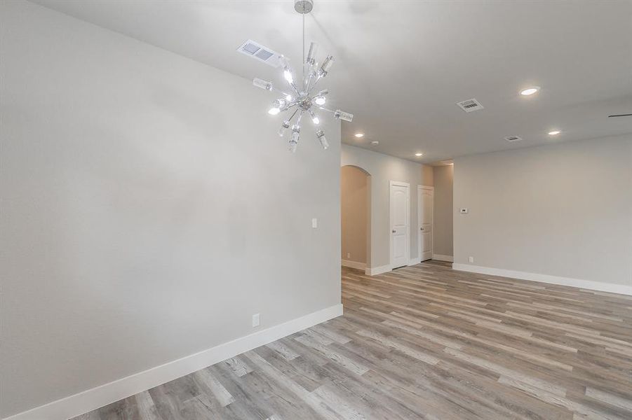 Empty room featuring a chandelier and light hardwood / wood-style flooring