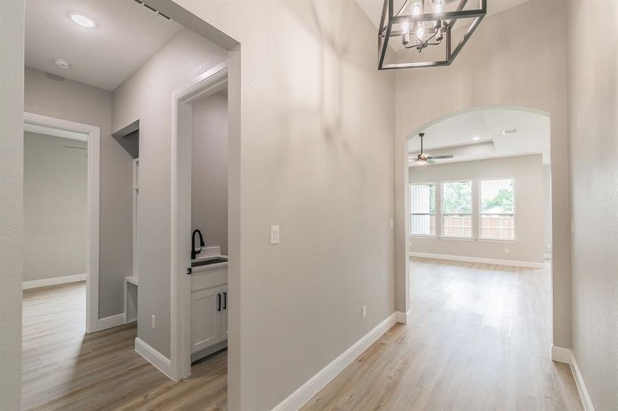Hall featuring light wood-type flooring, arched walkways, and baseboards Hall featuring light wood-type flooring, arched walkways, and baseboards
