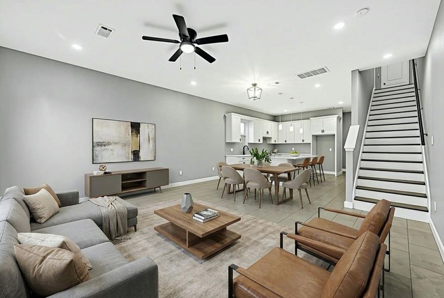 This photo showcases a modern open-concept living and dining area with neutral tones. It features a spacious layout, a stylish ceiling fan, and recessed lighting. The kitchen is equipped with contemporary white cabinetry and pendant lighting. A staircase leads to the upper level, adding to the home's elegant design.