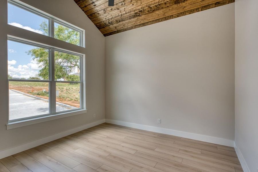 A window-filled room with a vaulted wood-paneled ceiling and plank flooring.